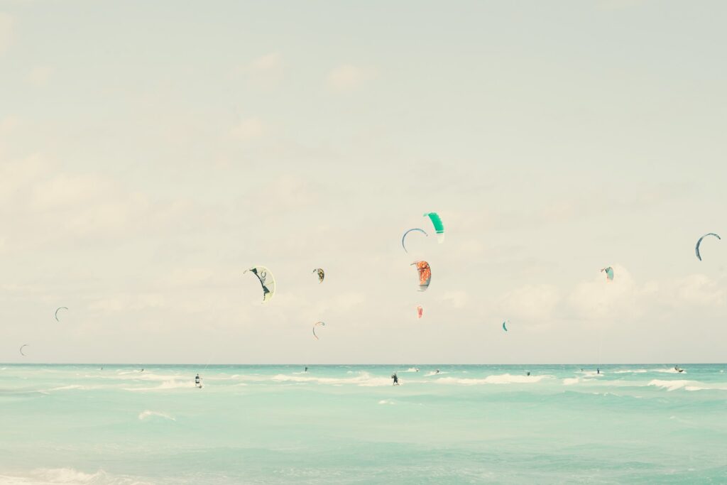 A kitesurfer catching air above the waves on Paje Beach, Zanzibar."
"Beginner kitesurfing lesson at Paje Beach, with an instructor guiding a student in shallow waters."
"A panoramic view of Paje Beach, Zanzibar, with kitesurfers in the distance and turquoise waters meeting the sandy shore."
"Palm trees lining the white sandy shores of Zanzibar Island under a clear, sunny sky."
"The entrance of a kitesurf school in Paje, Zanzibar, featuring surfboards and kites ready for lessons."
"A group of kitesurfing students preparing their kites on the beach at a kitesurf school in Zanzibar."
"Traditional dhow sailing near the coast of Zanzibar Island at sunset, reflecting the island’s rich cultural heritage."
"Stone Town’s vibrant market, showcasing the cultural side of Zanzibar, with colorful stalls and local products."